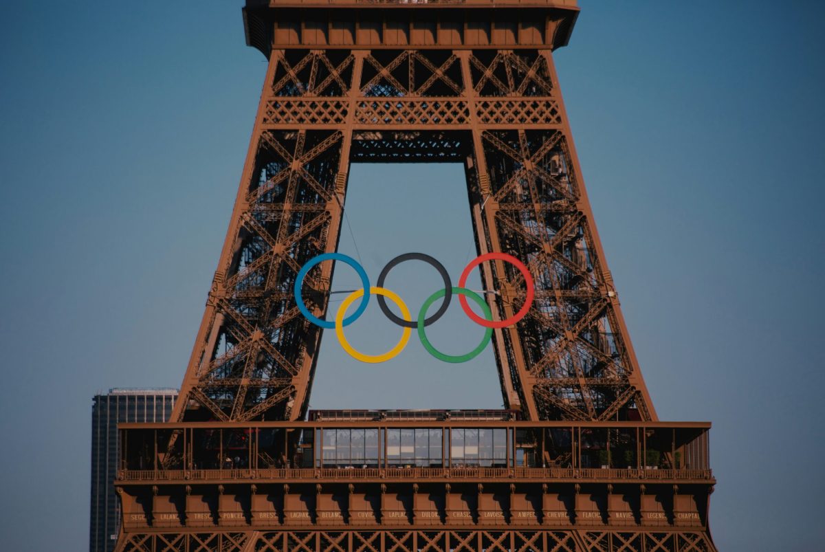 The Olympic rings mounted on the Eiffel Tower against a clear blue sky